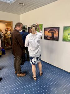 Uczestnicy wernisażu rozmawiający przy obrazach eksponowanych w galerii Uczelni Łukaszewski.